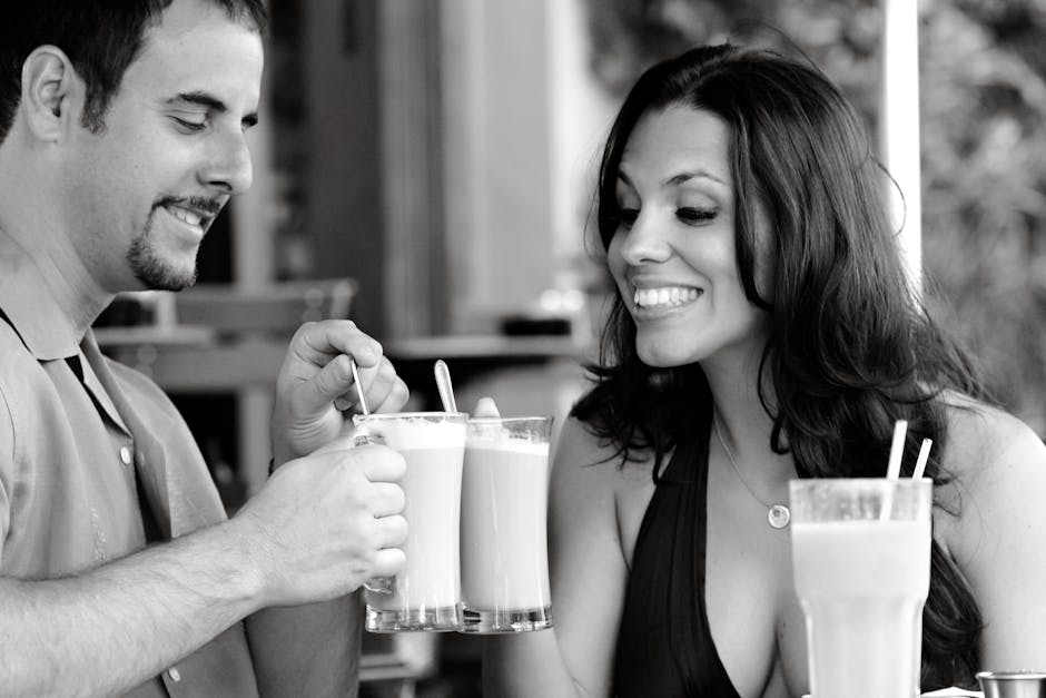 Miami Beach'teki açık hava kafesinde latte içen gülümseyen çift, neşeli bir anı paylaşıyor.