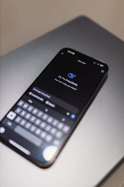 Dizüstü bilgisayar klavyesinde DeepSeek AI arayüzü bulunan akıllı telefon, teknoloji ve inovasyonu sergiliyor.