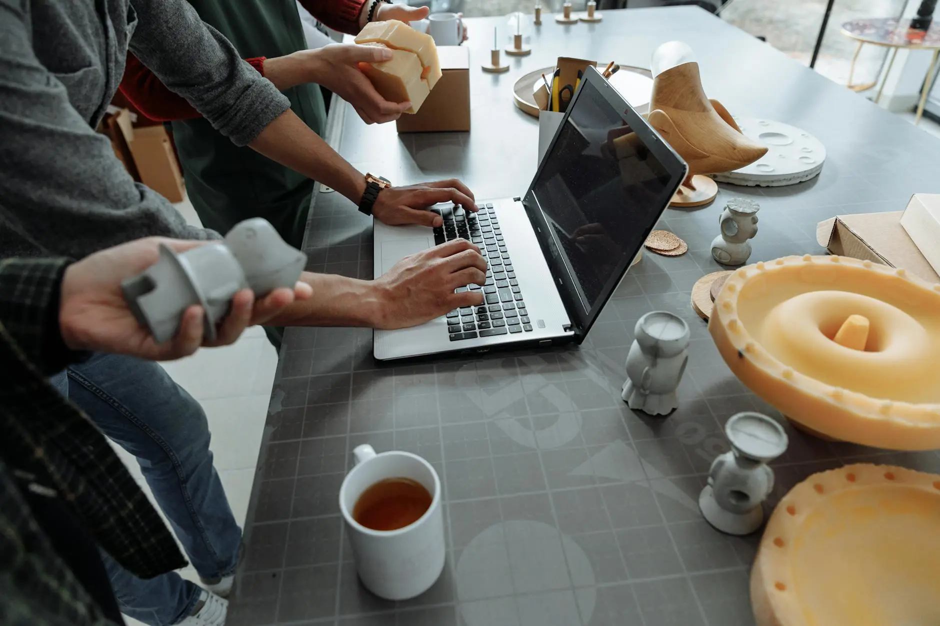 Hands working on a laptop with prototype models on the desk during product development