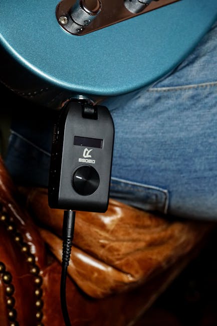 Deri sandalyenin üzerinde duran ses cihazı takılı elektro gitar.