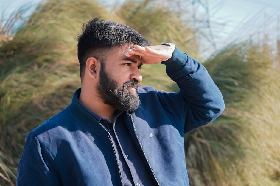 Güneşli bir günde gözlerini güneşten koruyan, uzaklara bakan bir adam.