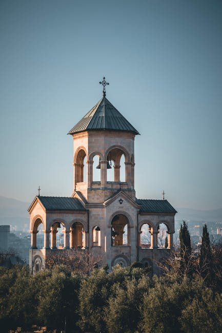 Gürcistan'ın Tiflis şehrindeki tarihi bir çan kulesinin, sonbahar yapraklarıyla kaplı alacakaranlıkta çekilmiş muhteşem manzarası.