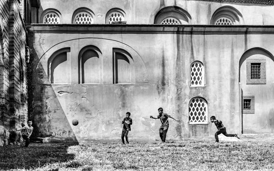 İstanbul'da tarihi bir caminin dışında futbol oynayan çocukların siyah beyaz fotoğrafı.
