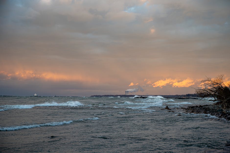 Doğa ve endüstrinin bir araya geldiği, görünür bacaların bulunduğu kayalık kıyı şeridi üzerinde dramatik gün batımı.