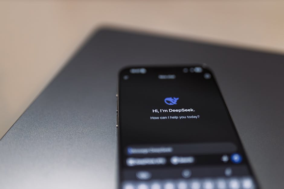 Dizüstü bilgisayarın üzerinde, ekranda AI asistan arayüzü bulunan bir akıllı telefonun yakın çekimi.