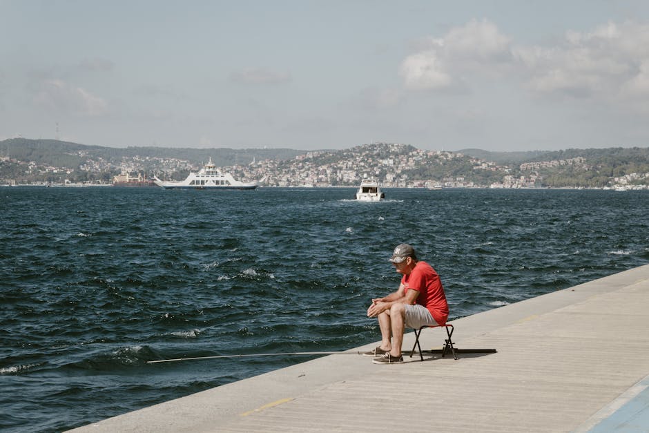 İstanbul Boğazı kıyısında balık tutan adam, güneşli bir günde görüntülendi.