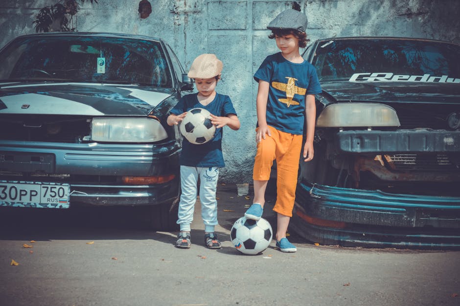 Arabaların Yanında Futbol Topu Oynayan Iki Erkek