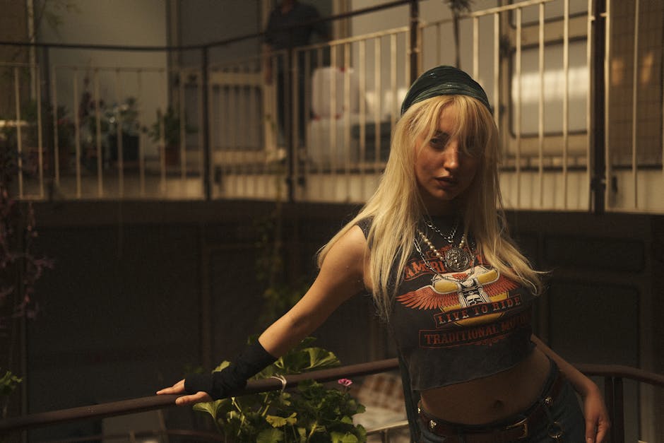 Sarı saçlı şık kadın, içeride korkuluğa yaslanmış, kendine güvenen bir tavır sergiliyor.