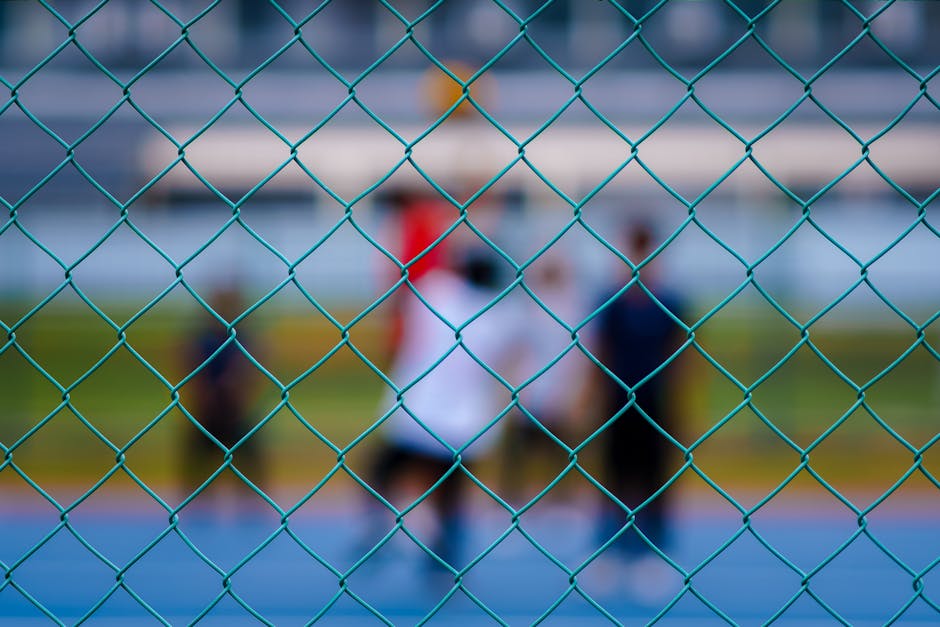 Dışarıda mavi zincir bağlantılı çitin arkasında spor yapan insanların bulanık görüntüsü.