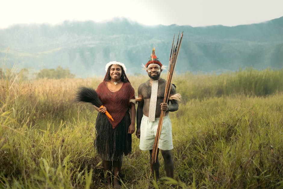 Geleneksel kıyafetli çift, dağlık bir arka planda yemyeşil bir çayırda duruyor.