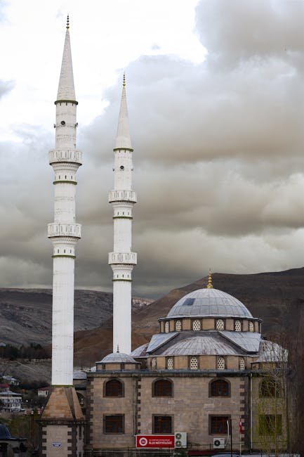 Dramatik bulutlu gökyüzünün önünde ikiz minarelere sahip muhteşem bir cami.