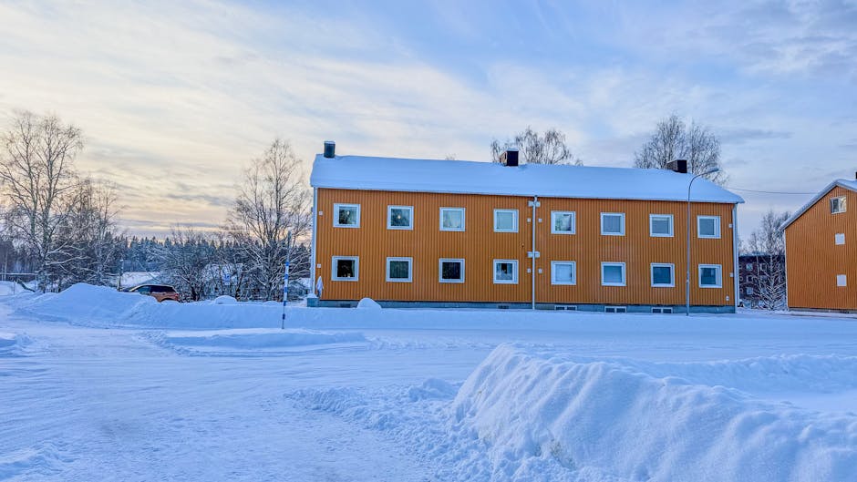 İsveç'in Boden kentinde karla çevrili turuncu bir binanın yer aldığı kış manzarası.