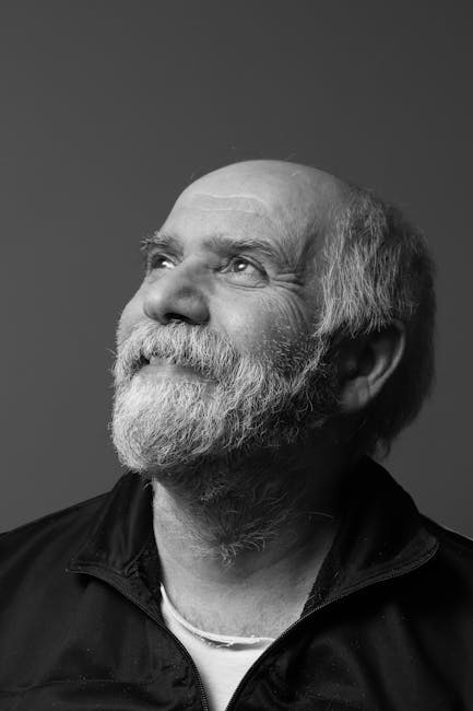 Sakallı yaşlı bir adam yukarıya doğru bakıyor; klasik siyah beyaz bir portrede bu an yakalanmış.